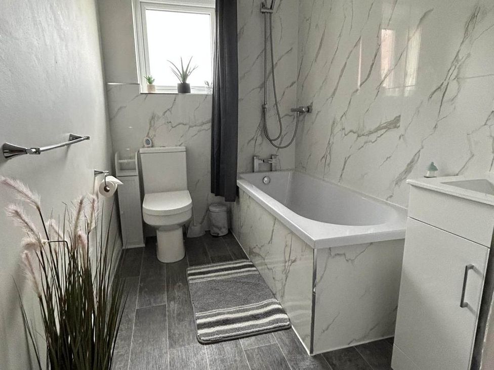 A bathroom with a bath tub, toilet, and sink at The Old Barn in Manchester