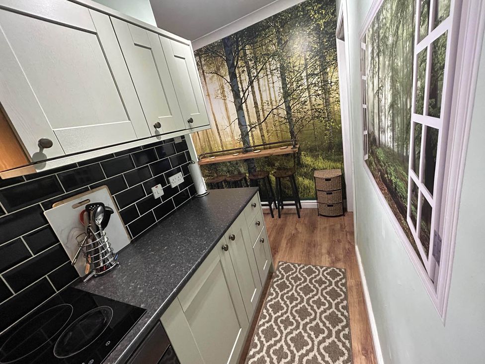 A kitchen with cabinets and stools at The Old Barn in Manchester