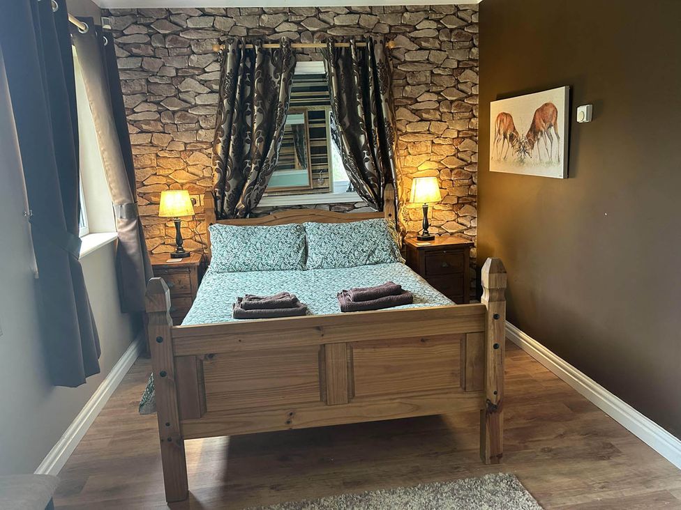 A bedroom with a wooden bed and patterned sheets at The Old Barn in Manchester