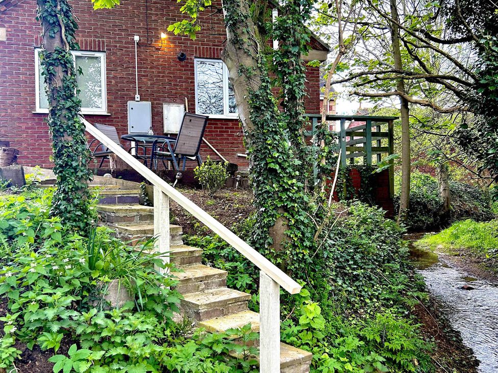 A garden with steps leading to a house and a river at the property