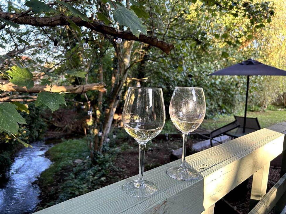 Two wine glasses on a deck near a creek at the property