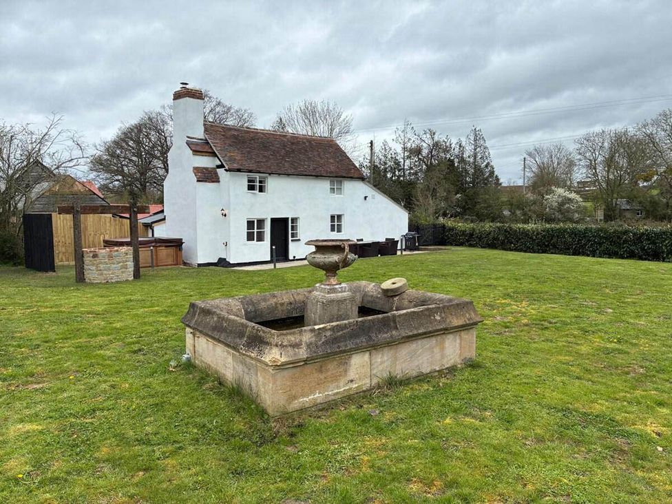 A garden with a fountain in front of a house at The Old Barn in Manchester