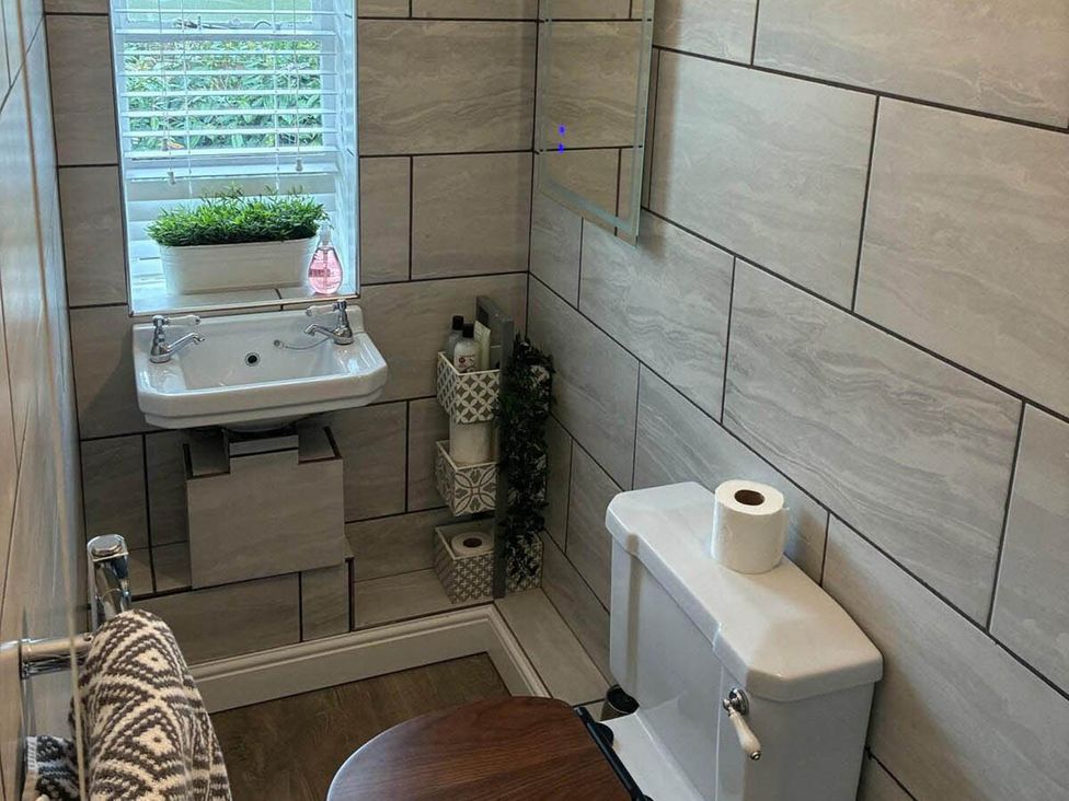 A bathroom with a sink, toilet, and mirror near a window