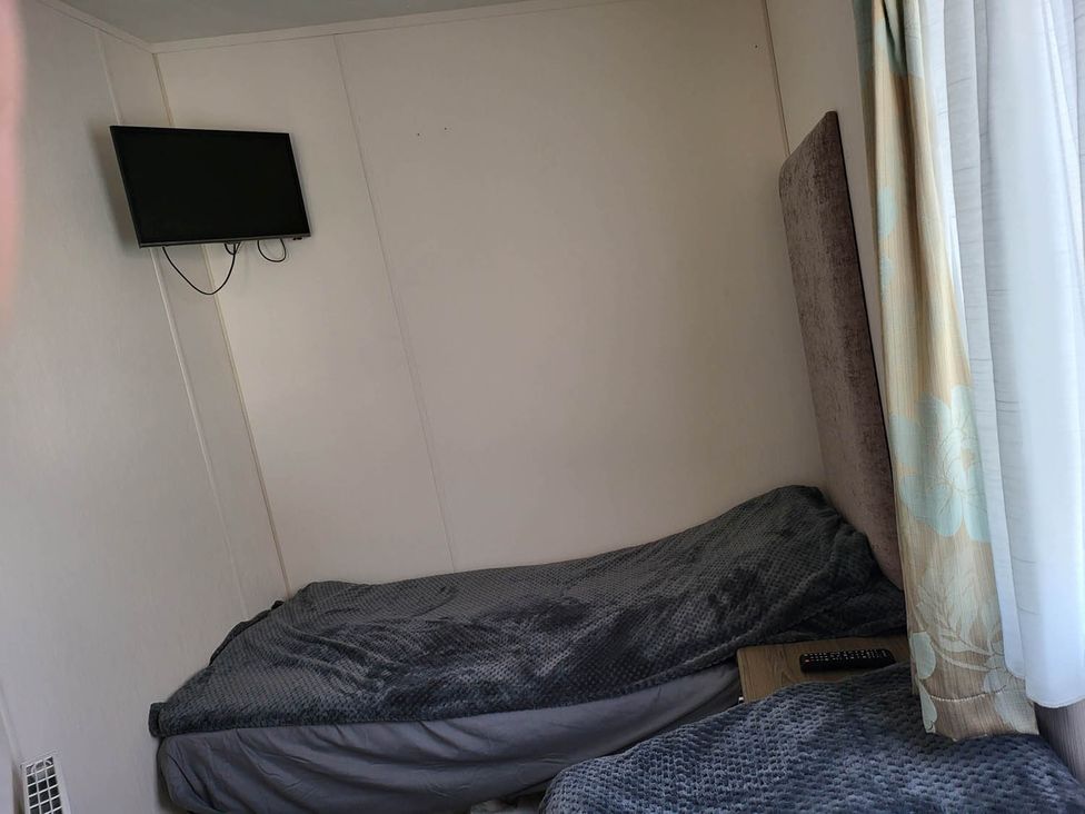 A bedroom with a bed and television mounted on the wall