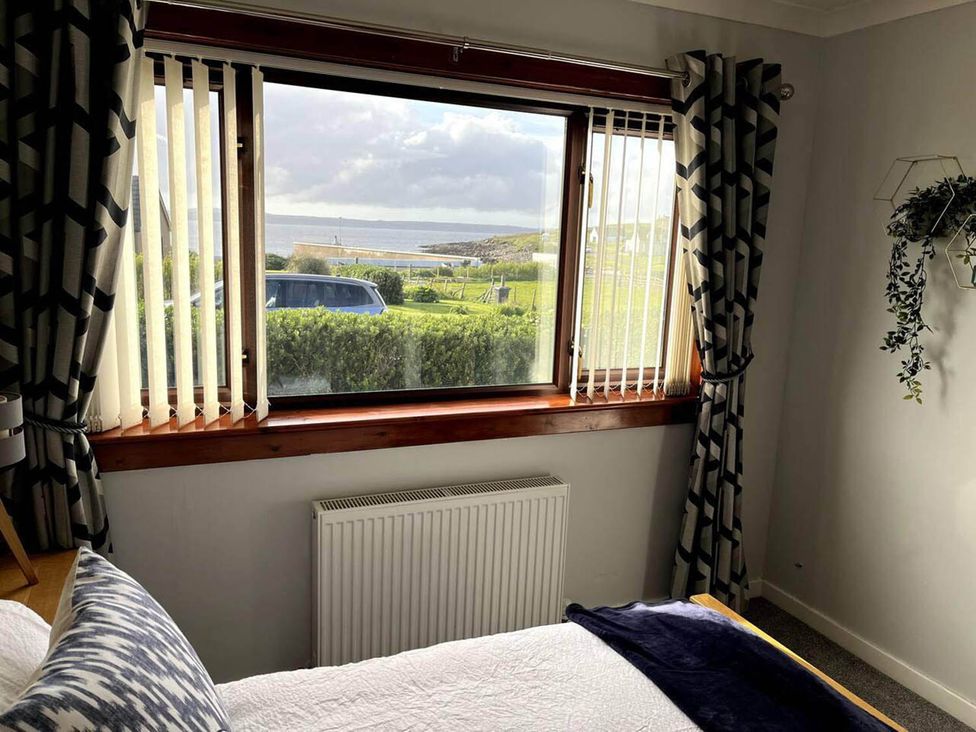 A bedroom with a window, curtains, and a view at an unspecified location