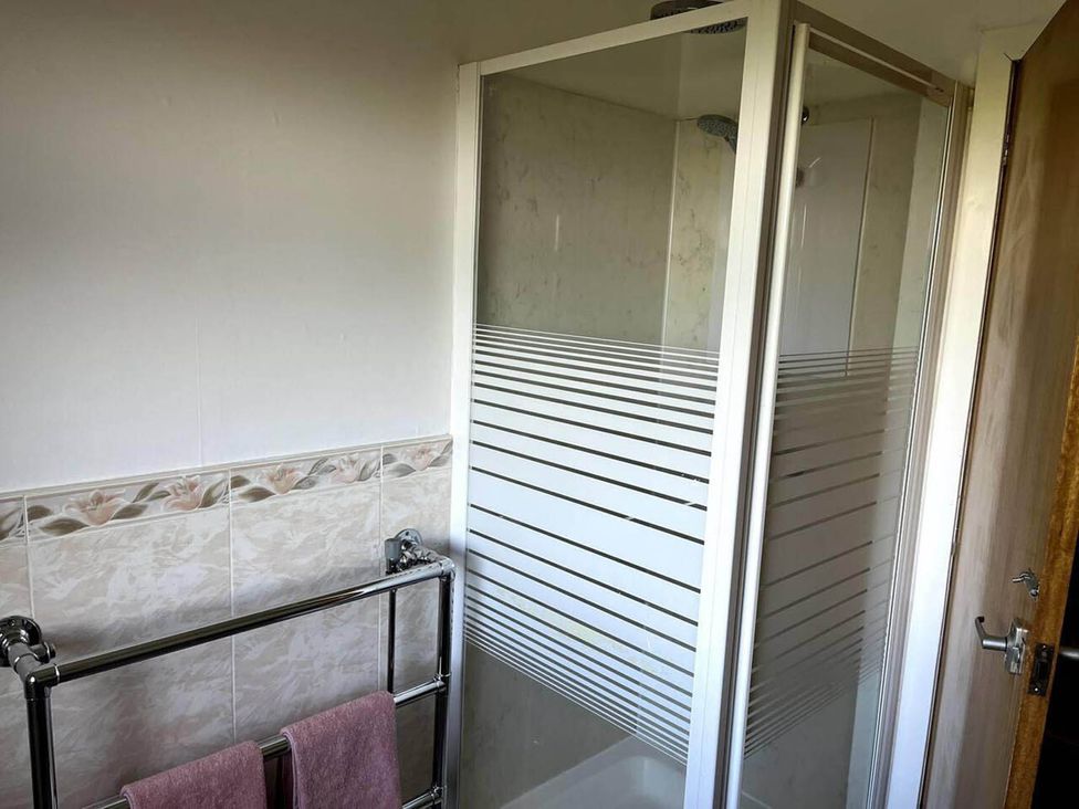 A bathroom with a shower enclosure and towel rack