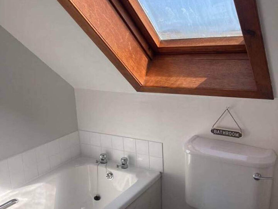 A bathroom with a bathtub, toilet, and window at the property