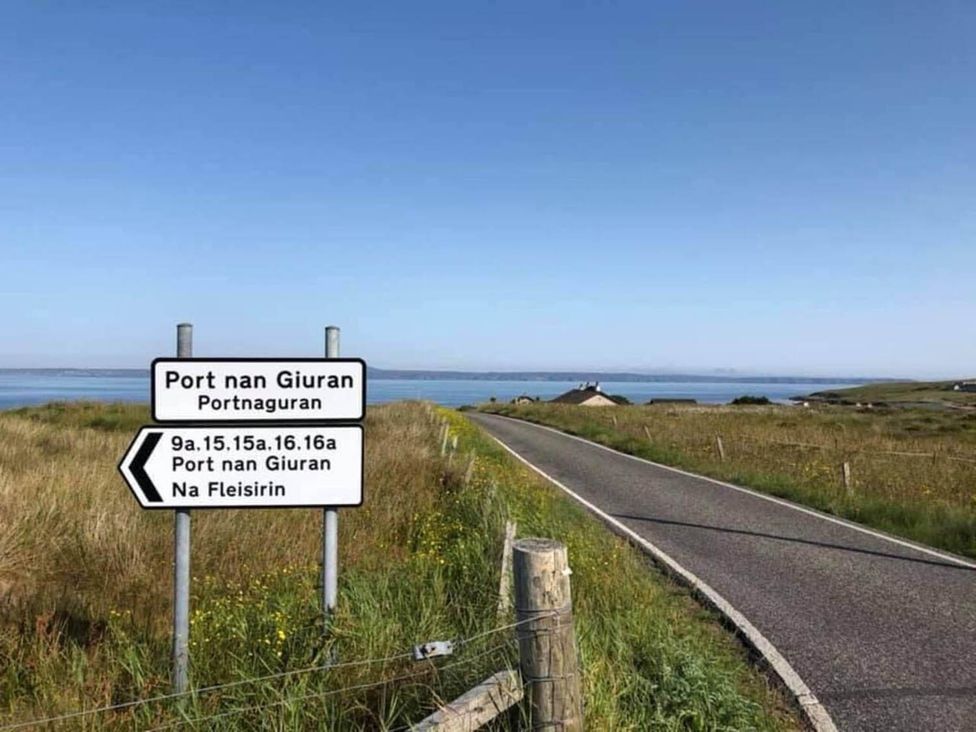 A sign for Port nan Giuran along a road near the sea