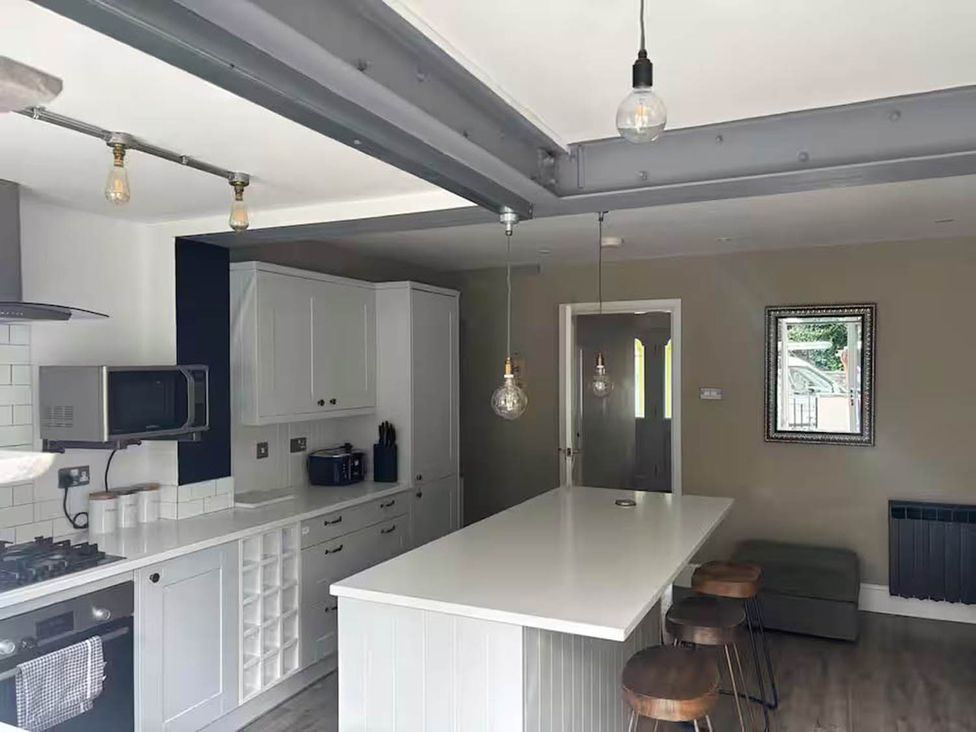 A kitchen with a countertop and bar stools at The Old Barn in Manchester