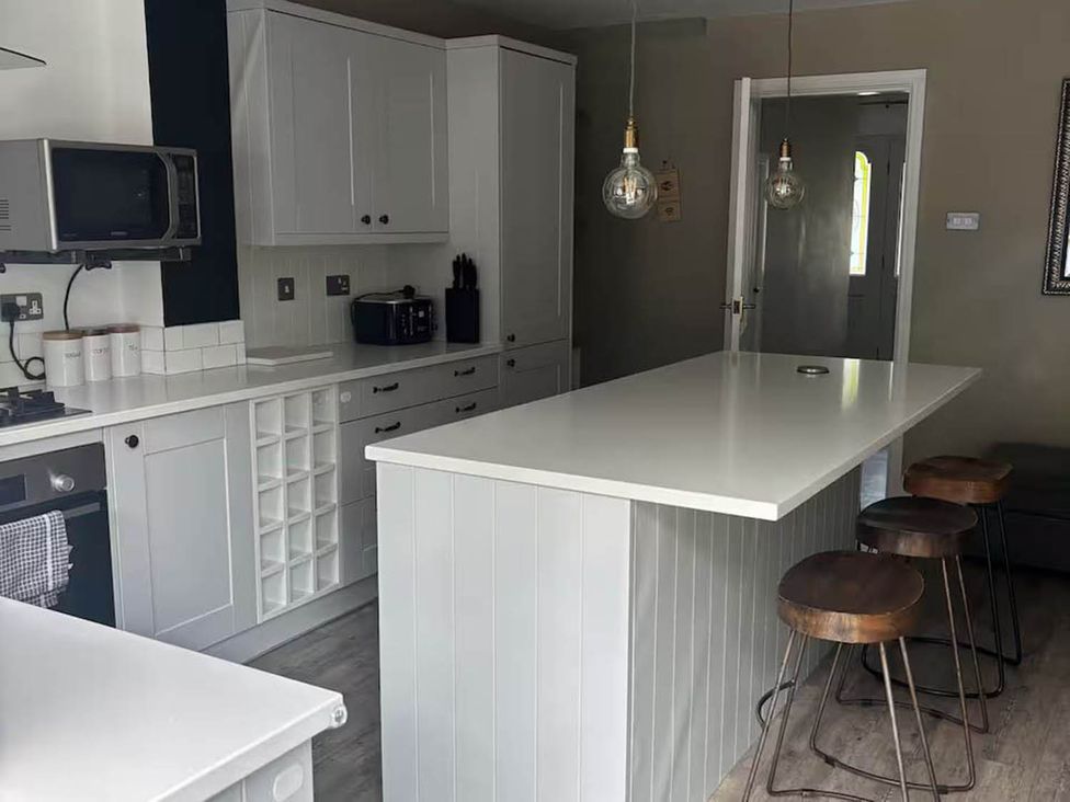A kitchen with a countertop and bar stools at the property location