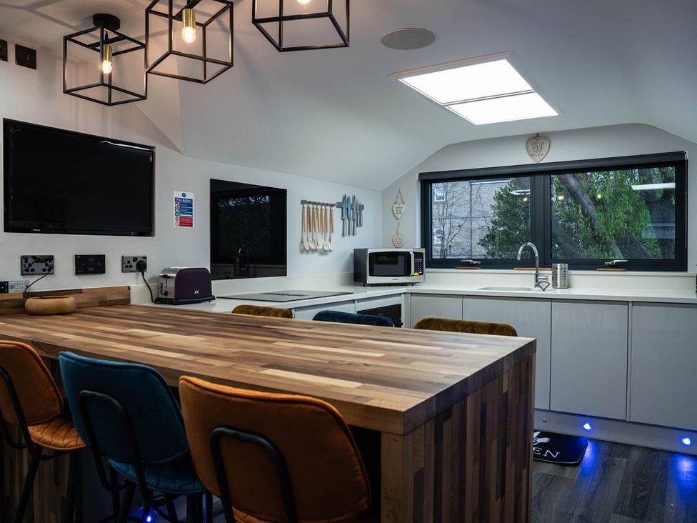 A kitchen with a wooden bar counter and various appliances including a microwave at The Old Barn in Manchester