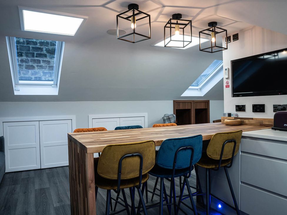 A kitchen with a bar countertop and stools at The Old Barn in Manchester