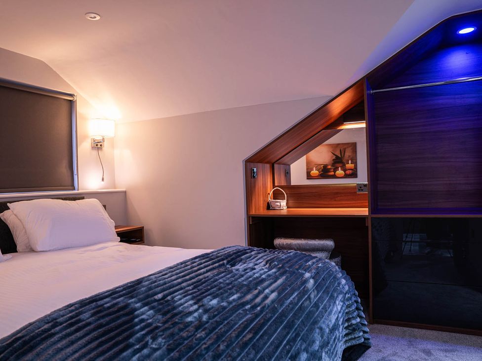 A bedroom with a bed, desk, and wall lamp at the property in unspecified location