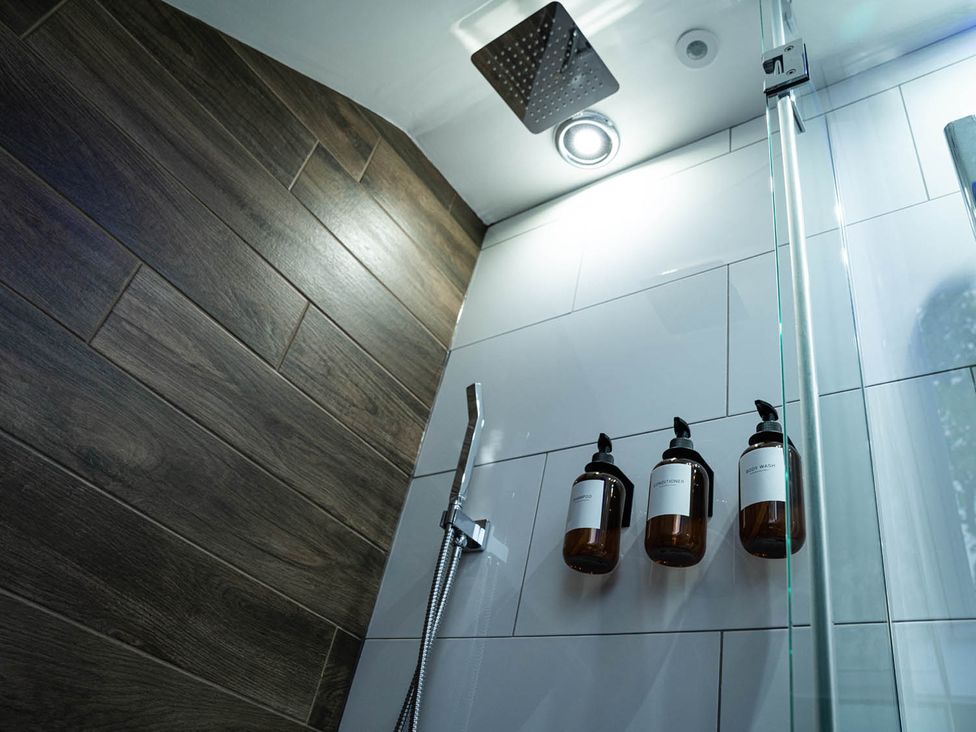 A shower area with a showerhead and liquid soap dispensers in a modern bathroom