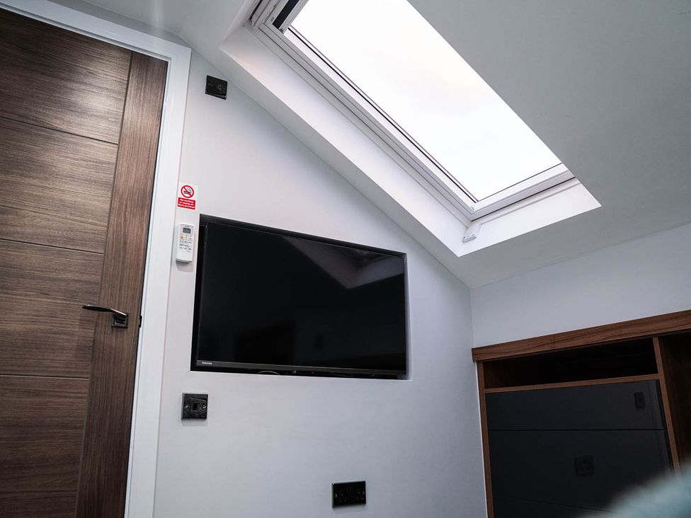 A TV mounted on the wall with a window and door at the property in 