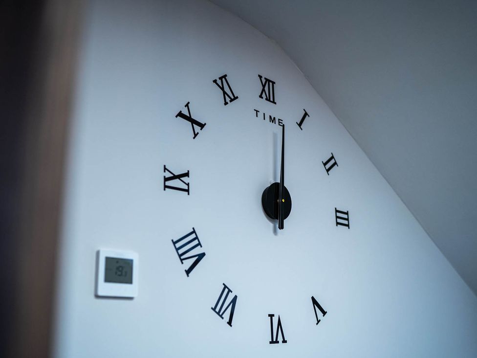 A wall clock and thermostat on a wall