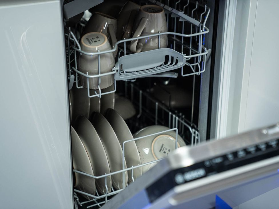 A dishwasher with cleaned dishes and cups at a kitchen