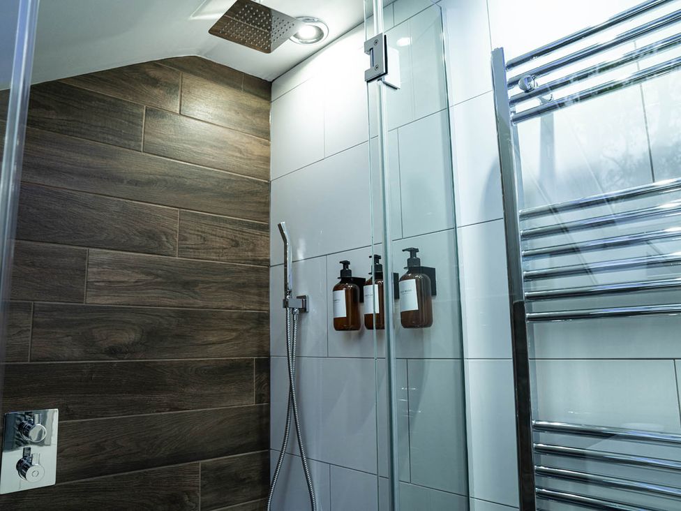 A shower with liquid soap dispensers and a towel radiator in a bathroom