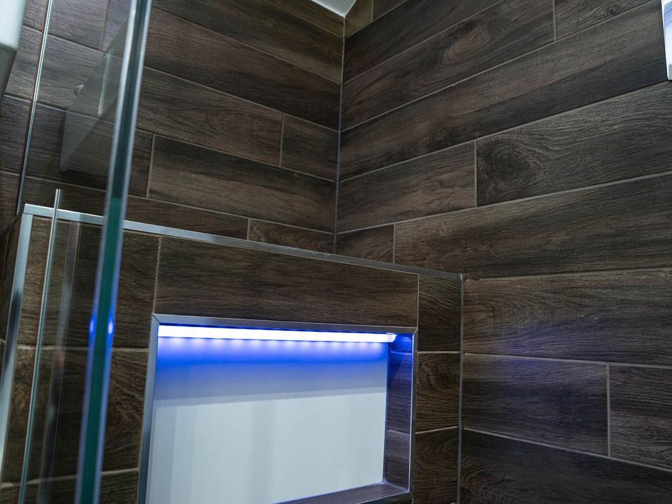 A bathroom with tiled walls and a built-in lighting feature