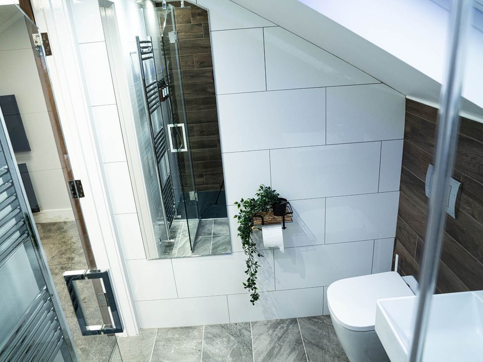 A bathroom with a shower, toilet, mirror, and towel holder