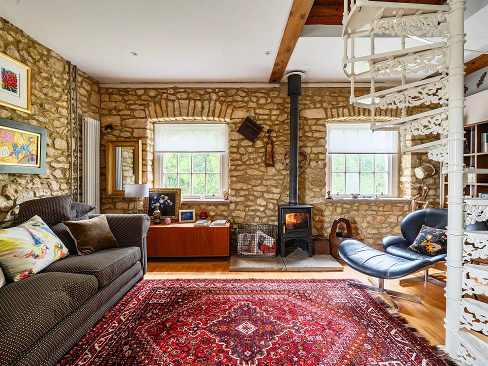 A living room with a sofa, rug, and stove at Beautiful Pad Near World Heritage Jurassic Coast, Pymore near Bridport