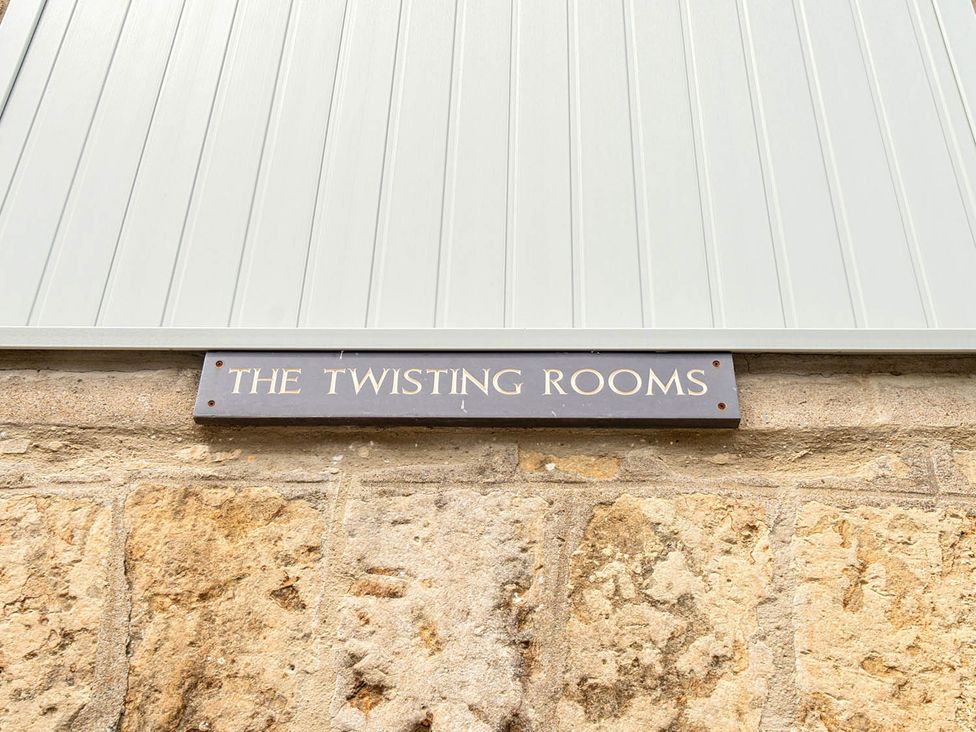 A sign reading THE TWISTING ROOMS on a stone wall