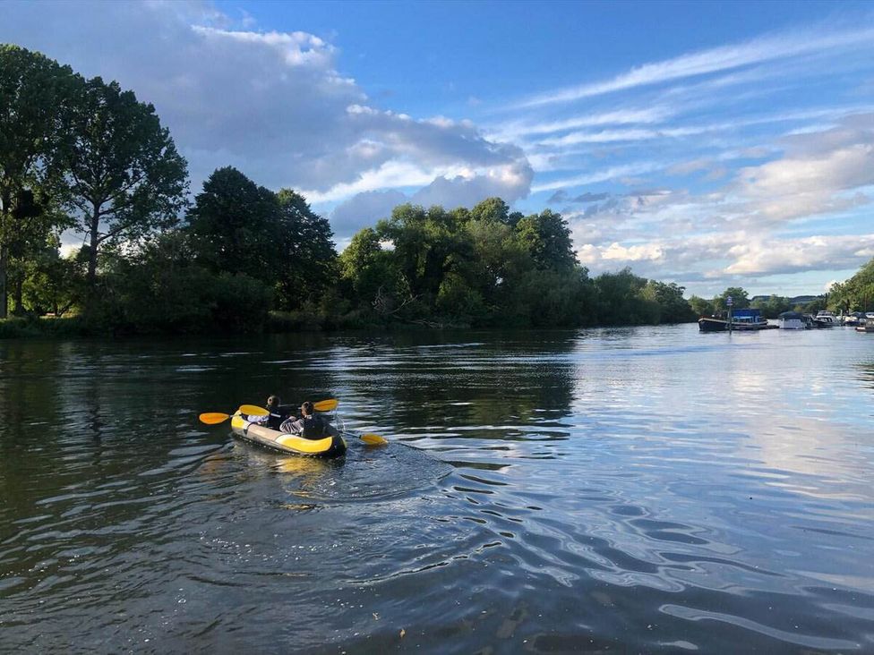 A kayak on a river with trees and boats in the background at Luxurious 5 Bedroom House in Cookham near Marlow