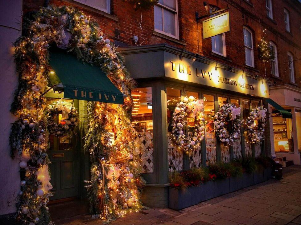 An entrance to a restaurant with wreaths and lights at The Ivy in Marlow