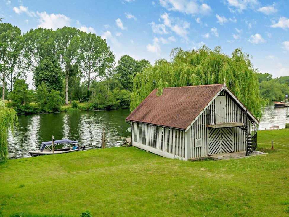 A shed by the river with a boat and trees at Luxurious 5 Bedroom House in Cookham near Marlow