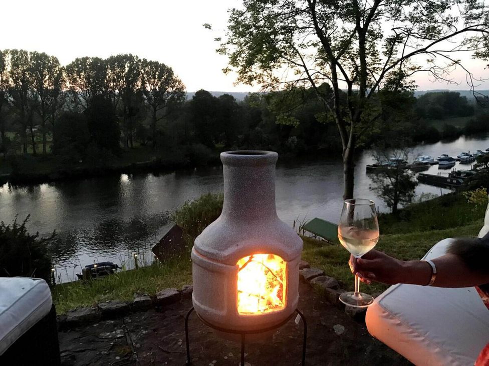 A fireplace by the river with a glass in hand at Luxurious 5 Bedroom House in Cookham near Marlow