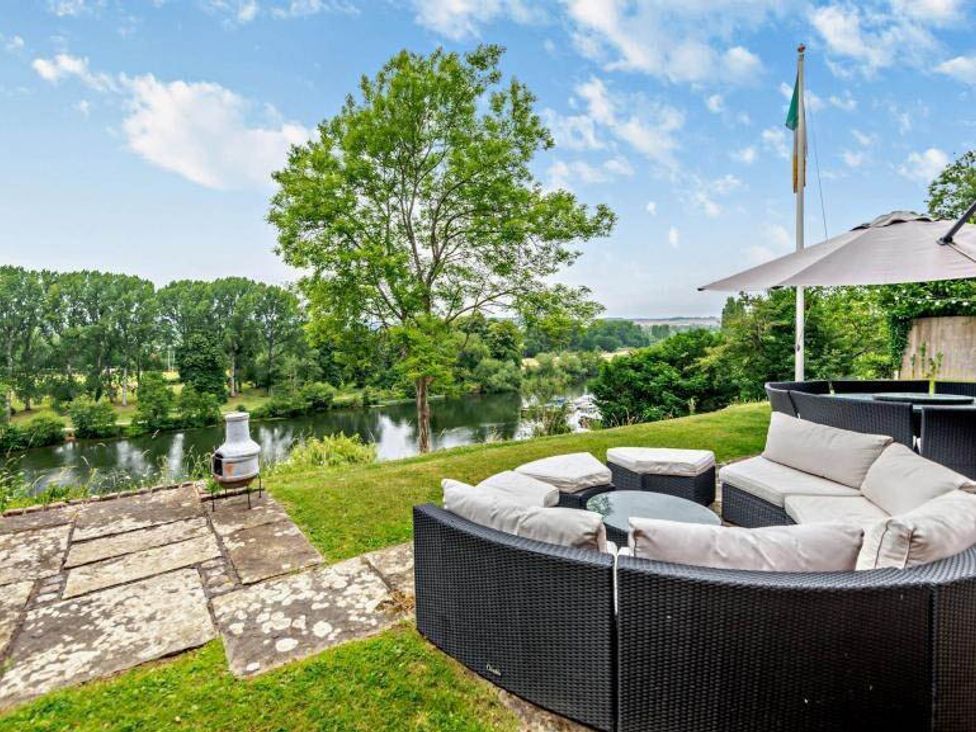 A garden with a seating area overlooking a river at Luxurious 5 Bedroom House in Cookham near Marlow