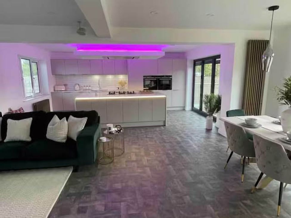 A living room with a sofa and kitchen units at Hot tub  BBQ  Garden Parking  Sleeps 8 Worcester