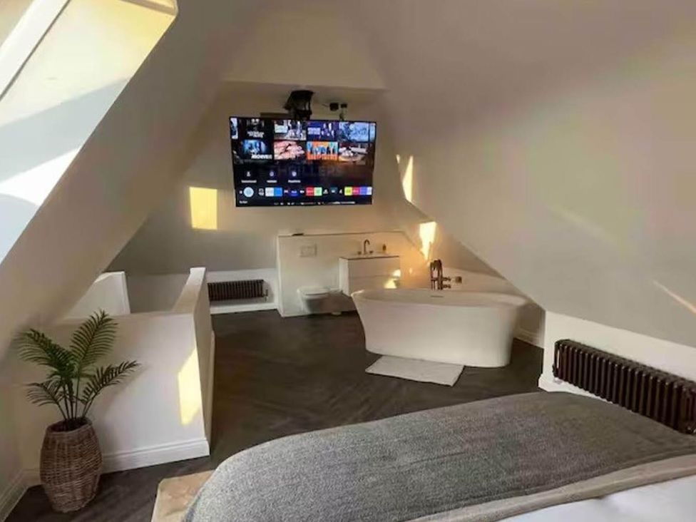 A bathroom with a bathtub and television at Hot tub BBQ Garden Parking Sleeps 8 Worcester