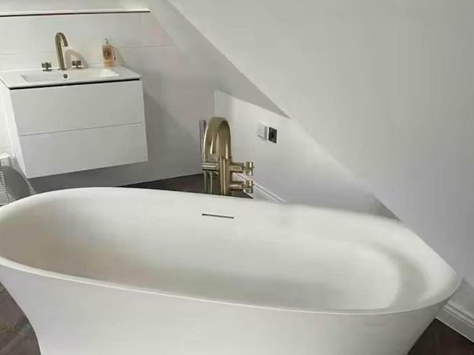 A bathroom with a bathtub and sink at Hot tub  BBQ  Garden Parking  Sleeps 8 Worcester