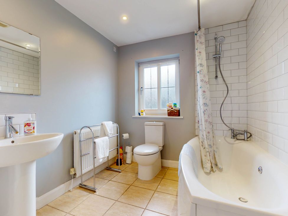 A bathroom with a bath tub, toilet, sink, and mirror at 5 Bedroom Home Sleeps 16 Ideal for Groups, Epworth