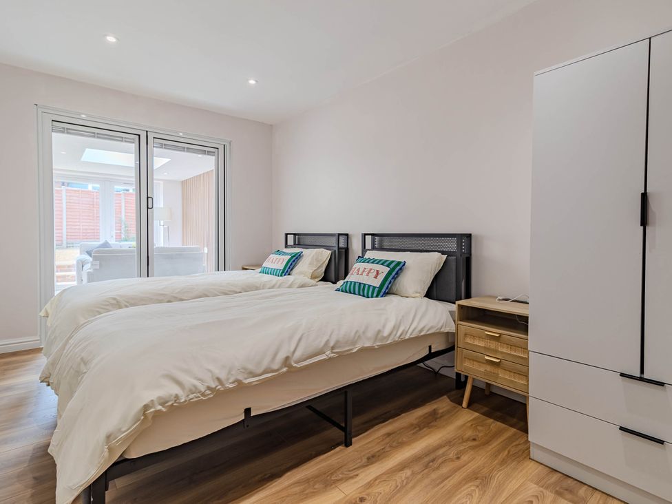A bedroom with two beds and a wardrobe at Loughborough Luxe Bungalow Retreat Sleeps 6 in Shepshed