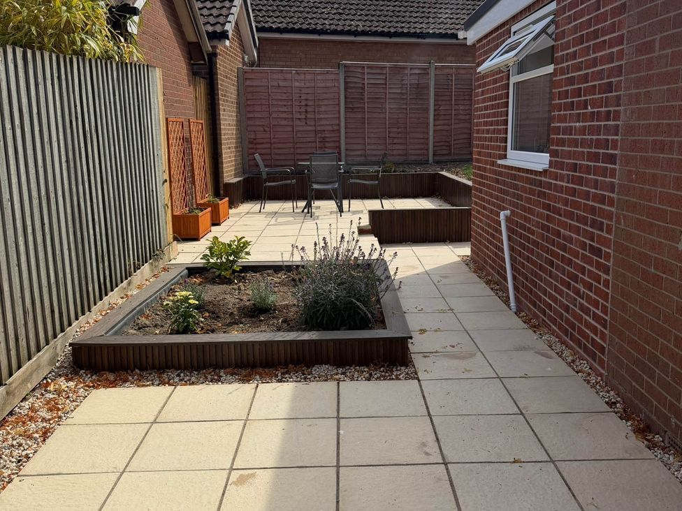 A garden area with paving stones and plant beds at Loughborough Luxe Bungalow Retreat Sleeps 6 Shepshed