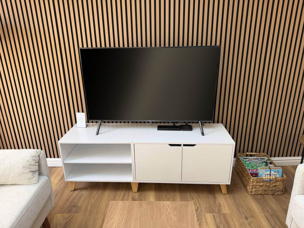 A living room with a television and a TV stand at Loughborough Luxe Bungalow Retreat Sleeps 6 in Shepshed