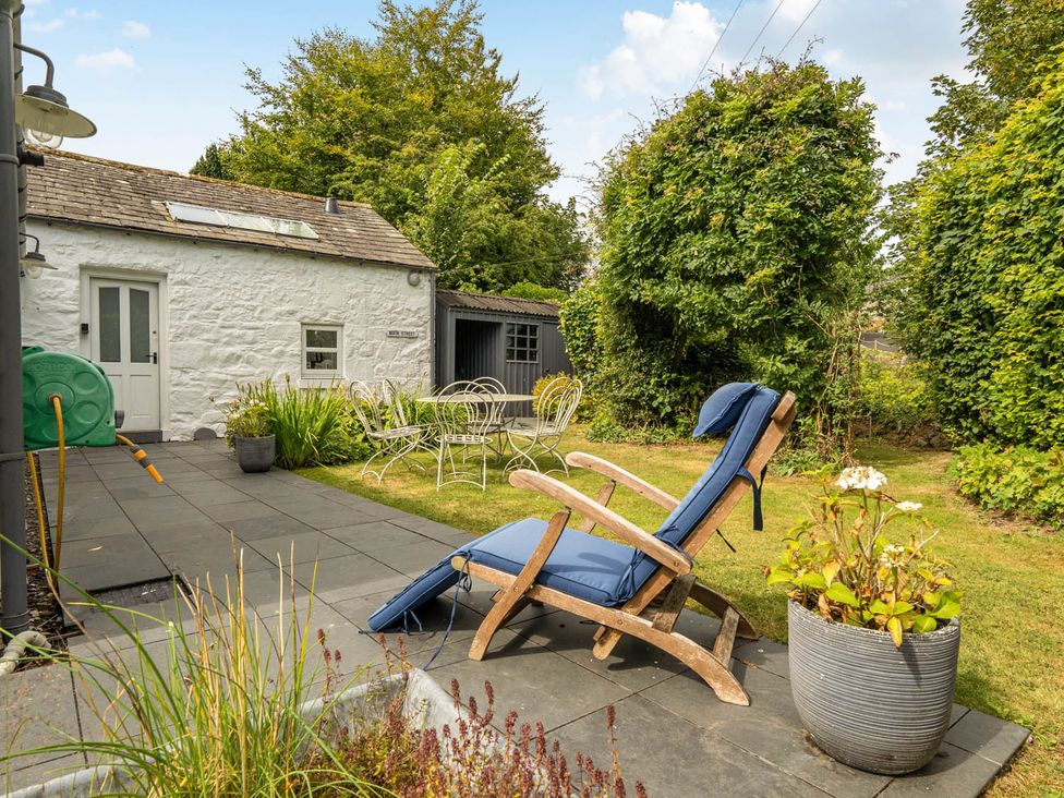 A garden with a patio, table, chairs, and a deck chair at House Sleeps 6 Pet Friendly Parking Auchencairn near Palnackie