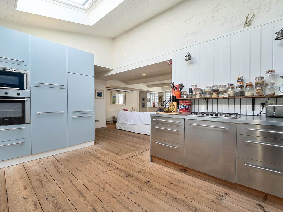 A kitchen with cabinets, appliances, and dining space at House Sleeps 6 Pet Friendly Parking Auchencairn near Palnackie