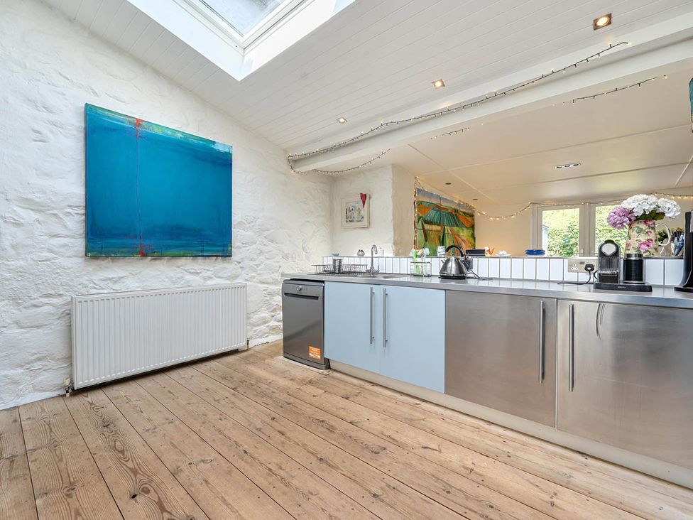A kitchen with stainless steel appliances and artwork at House Sleeps 6 Pet Friendly Parking Auchencairn near Palnackie