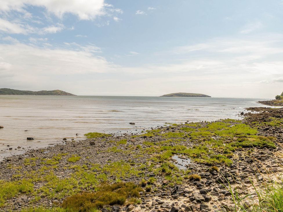A view of the shoreline with water and rocks at House Sleeps 6 Pet Friendly Parking Auchencairn near Palnackie