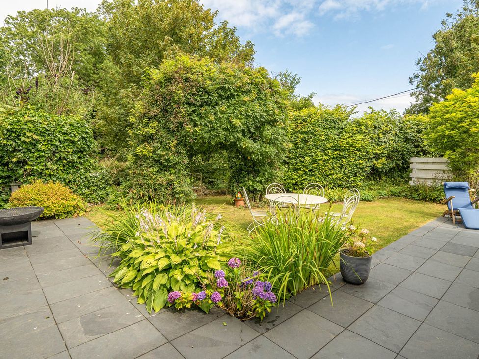 A garden with a table and chairs surrounded by greenery at House Sleeps 6 Pet Friendly Parking Auchencairn near Palnackie