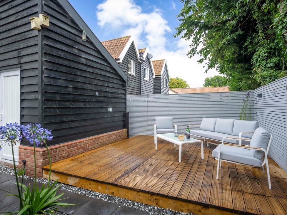 A wooden decking area with seating and a table at Detached House in Quiet Village Pets Allowed Ashbocking near Otley, Suffolk