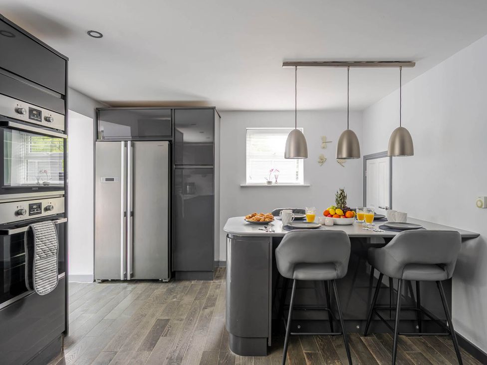 A kitchen with appliances and bar stools at Detached House in Quiet Village Pets Allowed Ashbocking near Otley, Suffolk