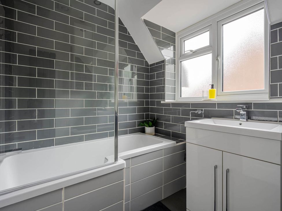 A bathroom with a bathtub, sink, and window at Detached House in Quiet Village Pets Allowed in Ashbocking near Otley, Suffolk