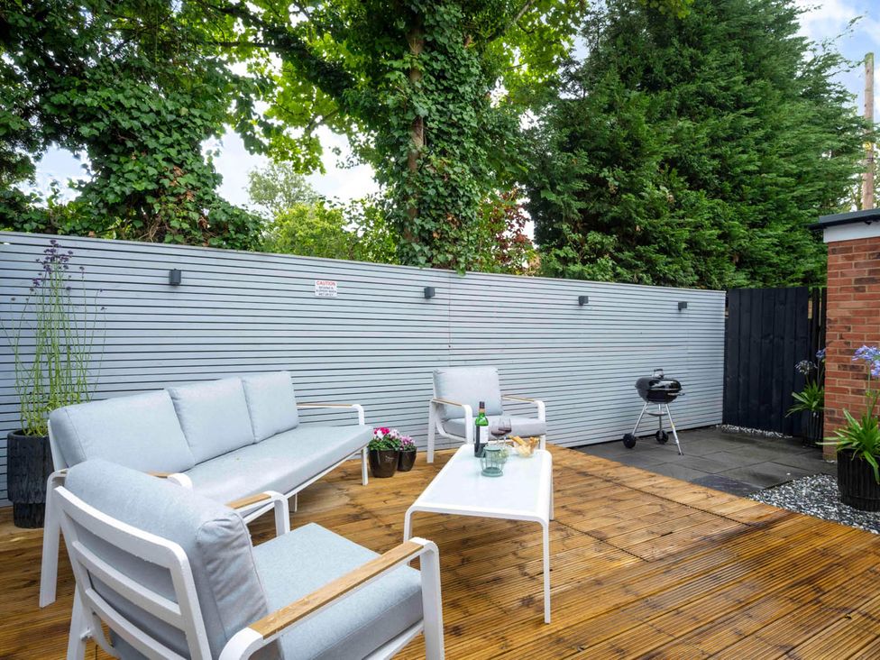 A garden area with a sofa, table, and grill at Detached House in Quiet Village Pets Allowed Ashbocking near Otley, Suffolk