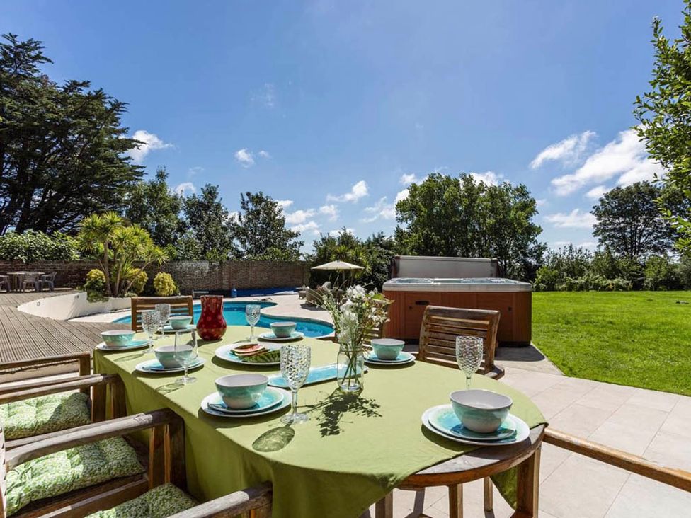 A dining area with a table and chairs beside a pool and hot tub at Sleeps 10 to 18 Parking Garden Pool Hot Tub Balcony in Friston