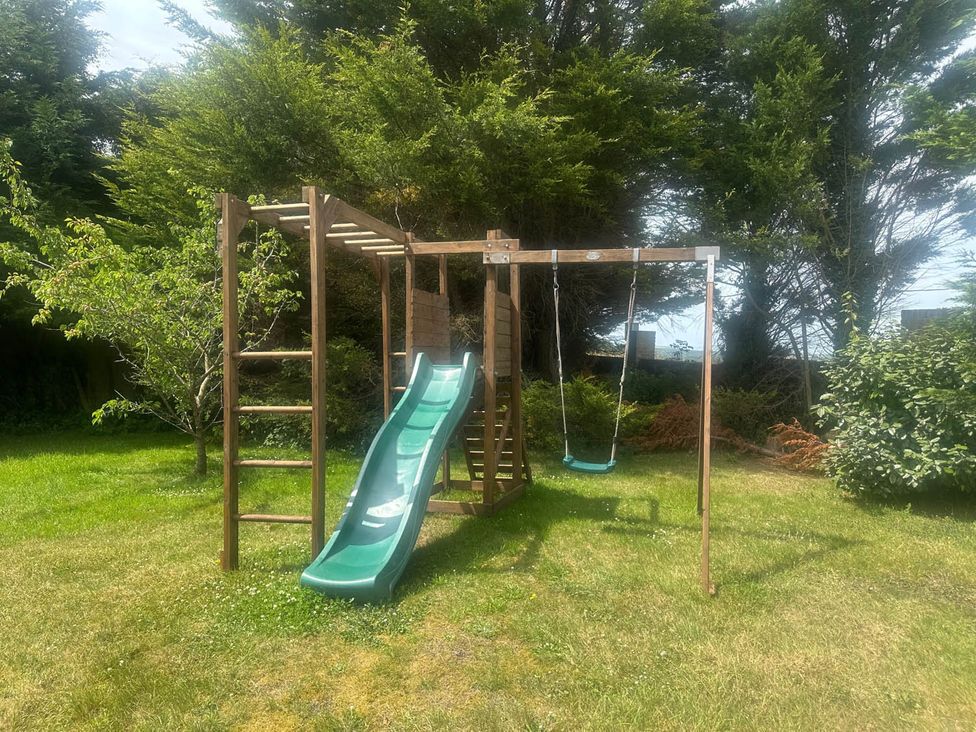 A playground with slide and swing in the garden at Sleeps 10 to 18 Parking Garden Pool Hot Tub Balcony in Friston