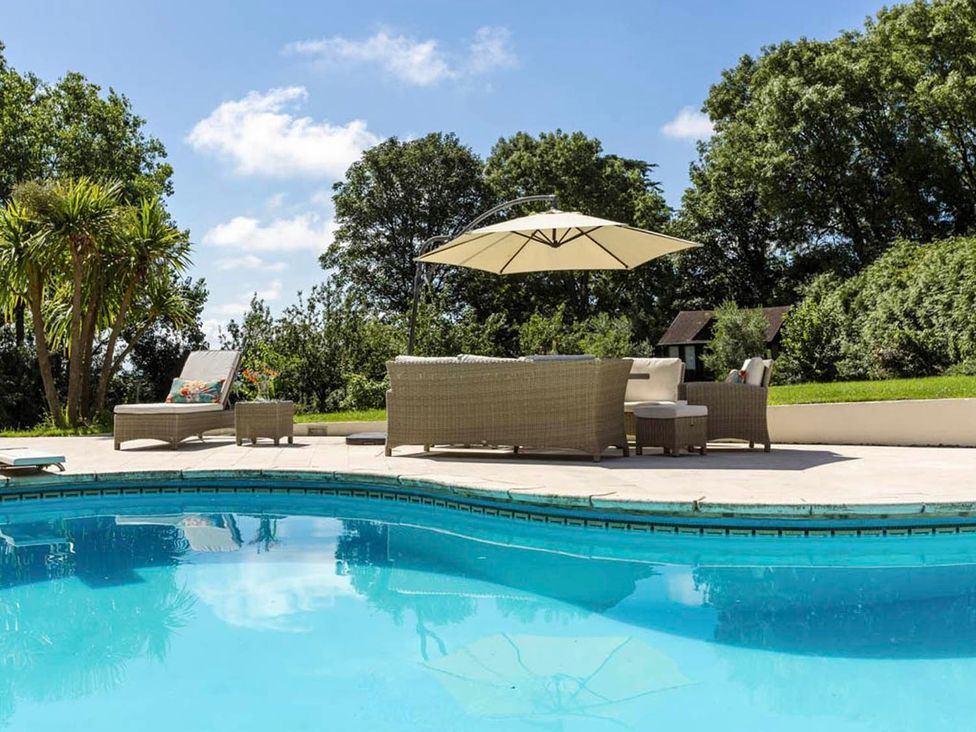 A pool area with lounge chairs and an umbrella at Sleeps 10 to 18 Parking Garden Pool Hot Tub Balcony in Friston